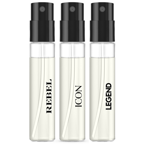 Three clear cylindrical perfume spray bottles with black atomizers, filled with pale cream liquid, labeled REBEL, ICON, and LEGEND on a white background.